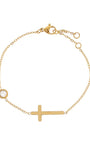 Gold bracelet with a cross and small round charm on a white background