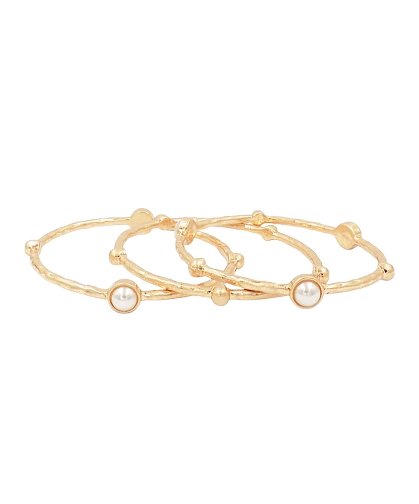 Three slim gold bangle bracelets with small bead details and round white pearl accents, arranged on a plain white background.