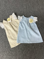 Children's outfit with a blue top and beige skirt on a gray background