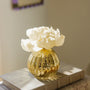 Gold textured vase with white flowers on a book