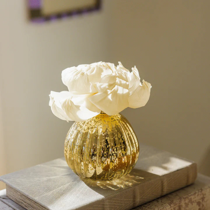 Gold textured vase with white flowers on a book
