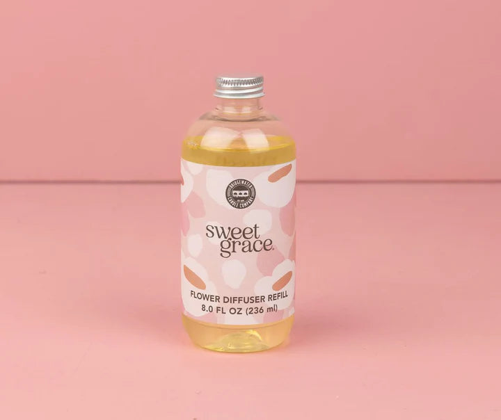 Bottle of 'sweet grace' flower diffuser refill on a pink background