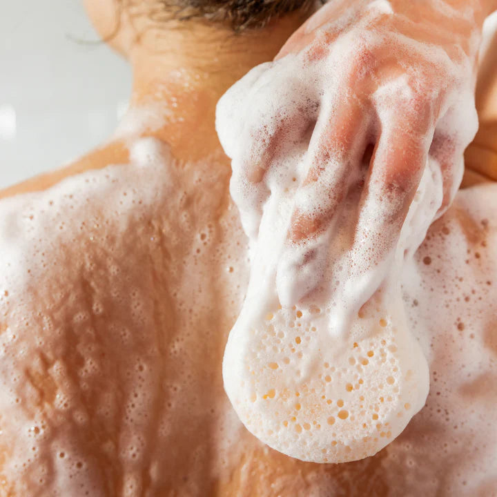 Close-up of a hand applying soap to skin with a focus on the lather.