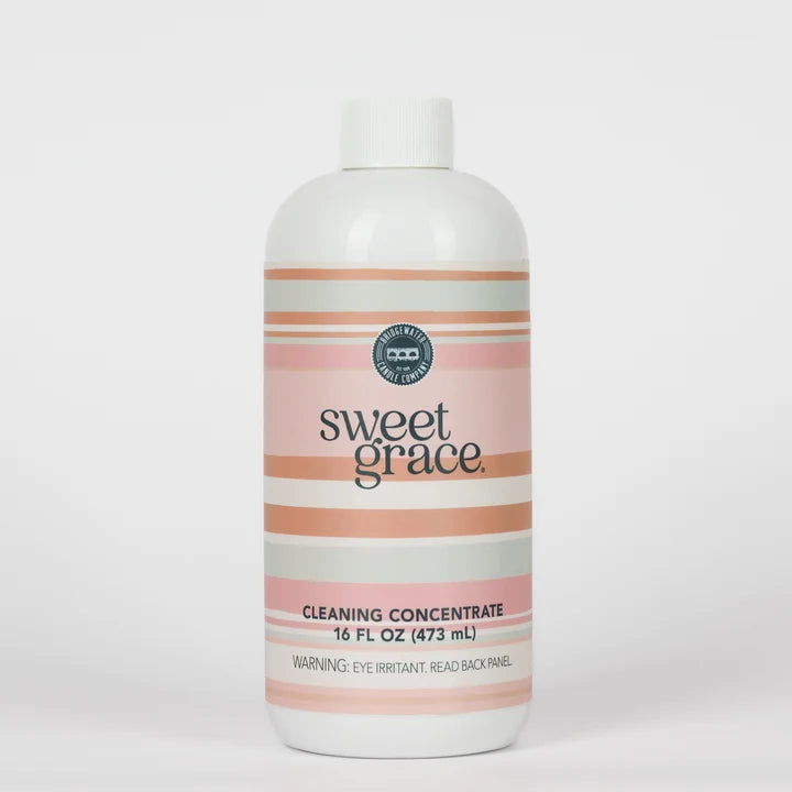 A 16 fl oz bottle of Sweet Grace Cleaning Concentrate with a white cap and a label featuring horizontal stripes in pink, peach, and light gray on a white background.