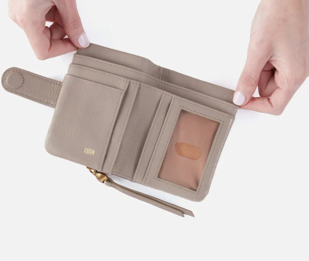 Beige wallet with a strap held open by hands on a white background