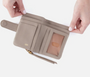 Beige wallet with a strap held open by hands on a white background