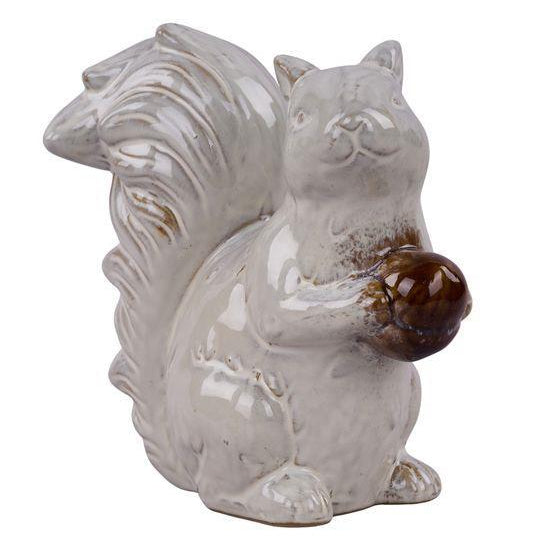 White ceramic squirrel figurine with a brown nut on a white background