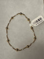 A beaded stretch bracelet with alternating metallic bronze and white beads, shown on a light gray textured background with a white product tag attached.
