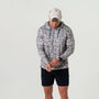 Person wearing a patterned hoodie and black shorts on a light gray background