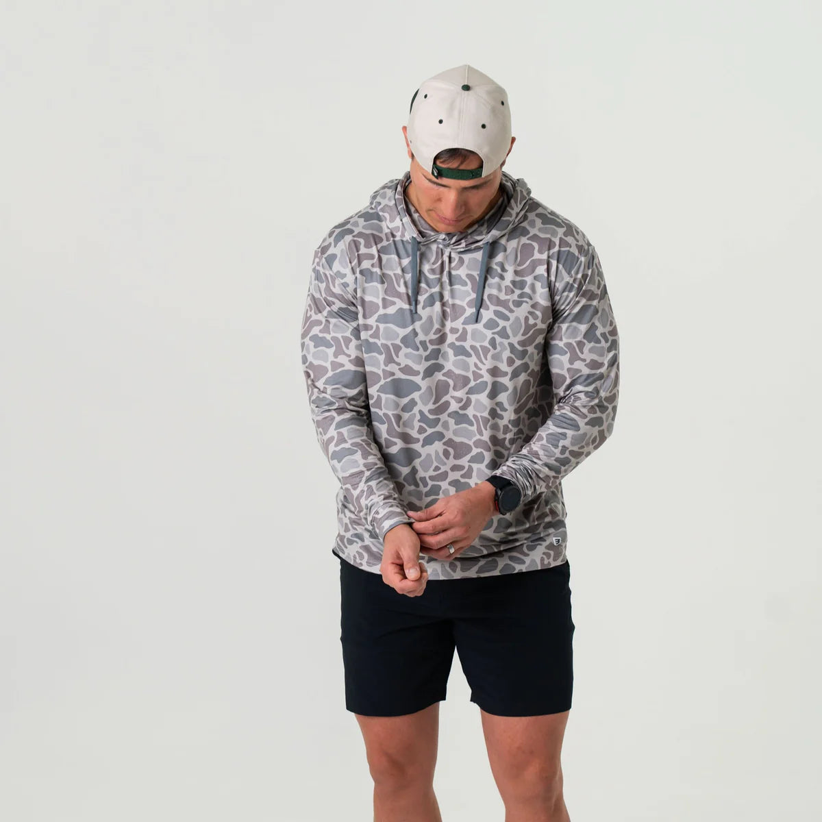 Person wearing a patterned hoodie and black shorts on a light gray background
