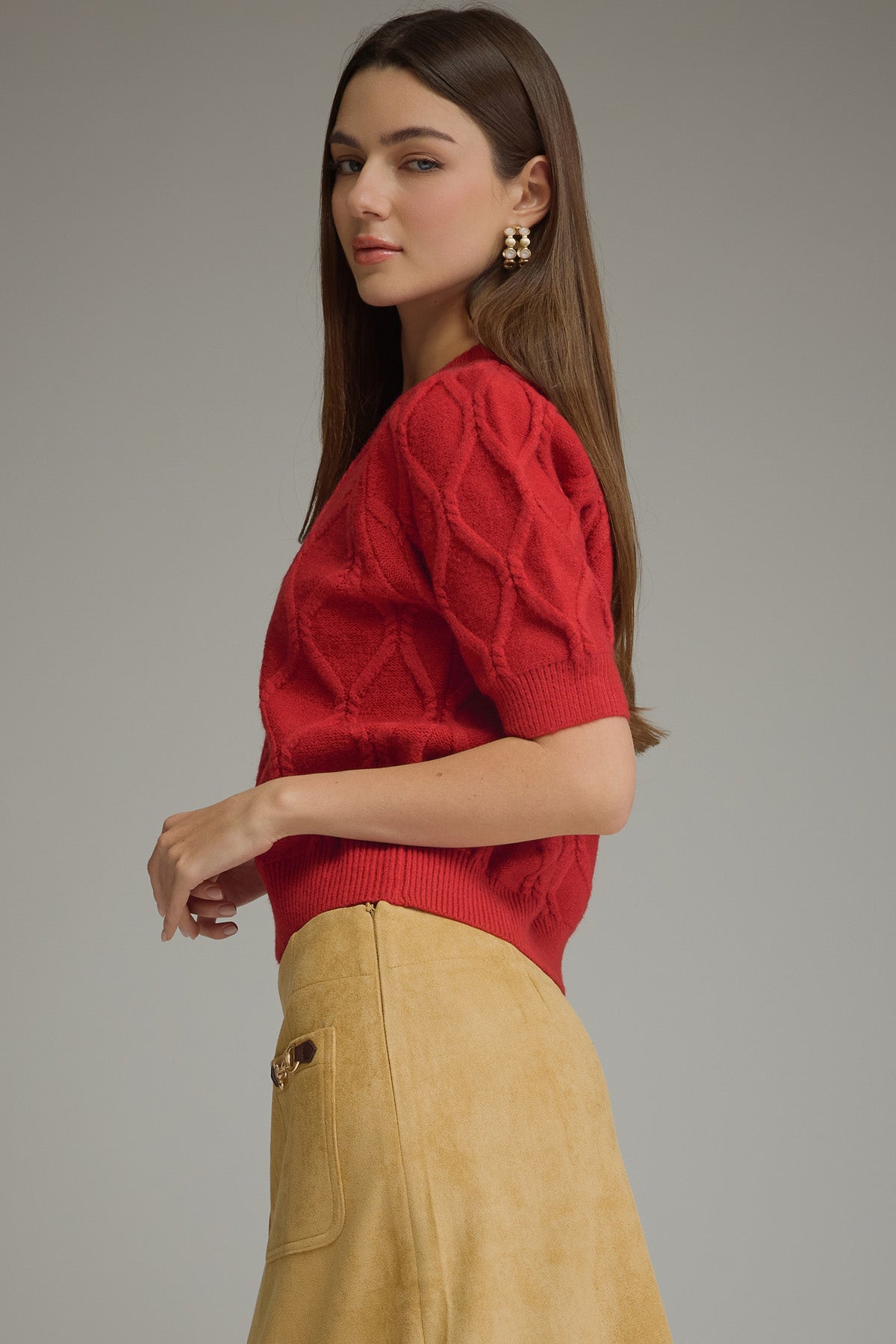 Woman wearing a red sweater with tan bottoms on white background