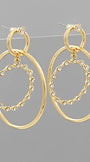 A pair of gold-toned drop earrings with large oval hoops and a smaller inner oval outlined with small clear rhinestones, shown against a plain gray background.