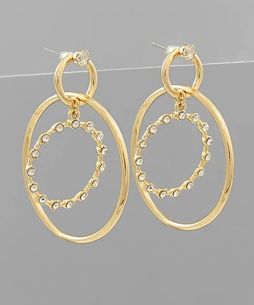 A pair of gold-toned drop earrings with large oval hoops and a smaller inner oval outlined with small clear rhinestones, shown against a plain gray background.