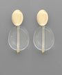 A pair of modern gold and clear acrylic drop earrings on a solid gray background.