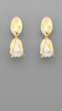 A pair of gold-toned drop earrings with a textured oval top and a tulip-shaped drop featuring a white pearl-like center, shown on a solid gray background.