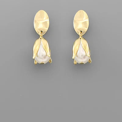 A pair of gold-toned drop earrings with a textured oval top and a tulip-shaped drop featuring a white pearl-like center, shown on a solid gray background.