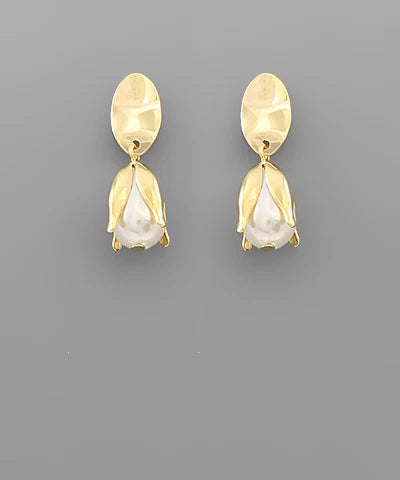 A pair of gold-toned drop earrings with a textured oval top and a tulip-shaped drop featuring a white pearl-like center, shown on a solid gray background.