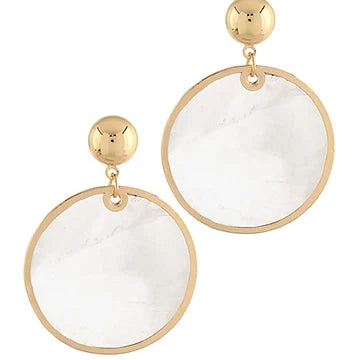 A pair of gold-tone drop earrings featuring large circular clear resin pendants with a subtle white marble pattern, suspended from polished gold ball studs.