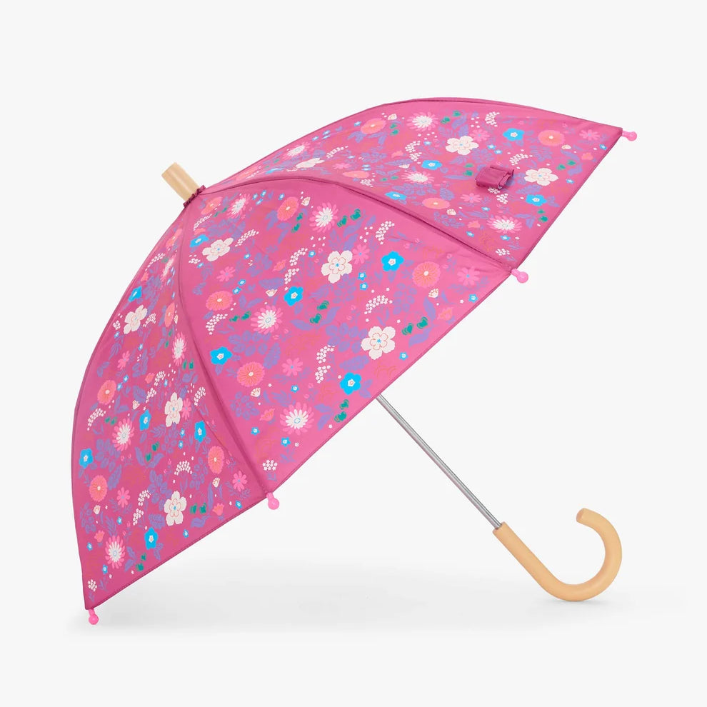 A pink umbrella with a colorful floral pattern, featuring a light wood handle and top cap, shown against a plain light gray background.