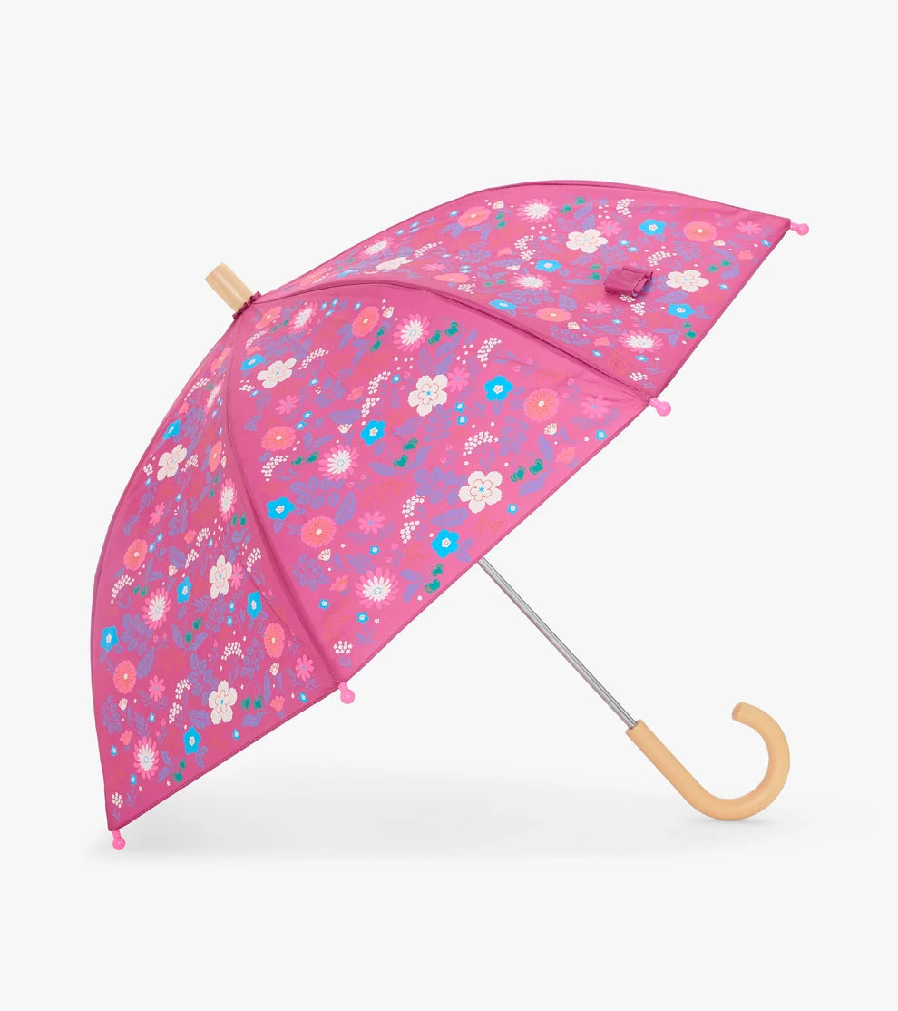 A pink umbrella with a colorful floral pattern, featuring a light wood handle and top cap, shown against a plain light gray background.