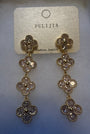 A pair of gold-tone dangle earrings with three floral clover motifs, each adorned with clear rhinestones, hanging from a textured beige card labeled 'FULIJIA'.