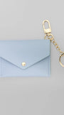 A light blue envelope-style card holder or coin purse with a gold snap button, attached to a gold keychain clasp and split ring, shown on a plain light gray background.