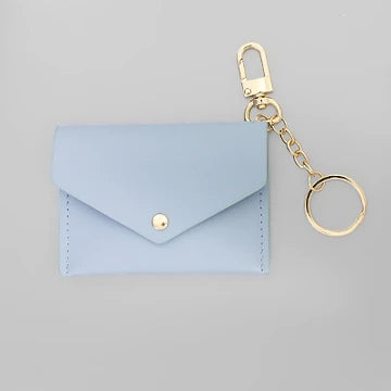 A light blue envelope-style card holder or coin purse with a gold snap button, attached to a gold keychain clasp and split ring, shown on a plain light gray background.