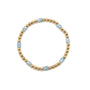 Bracelet with gold beads and light blue stones on a white background
