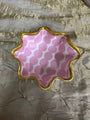 Decorative dish with pink and white pattern on a textured gold surface