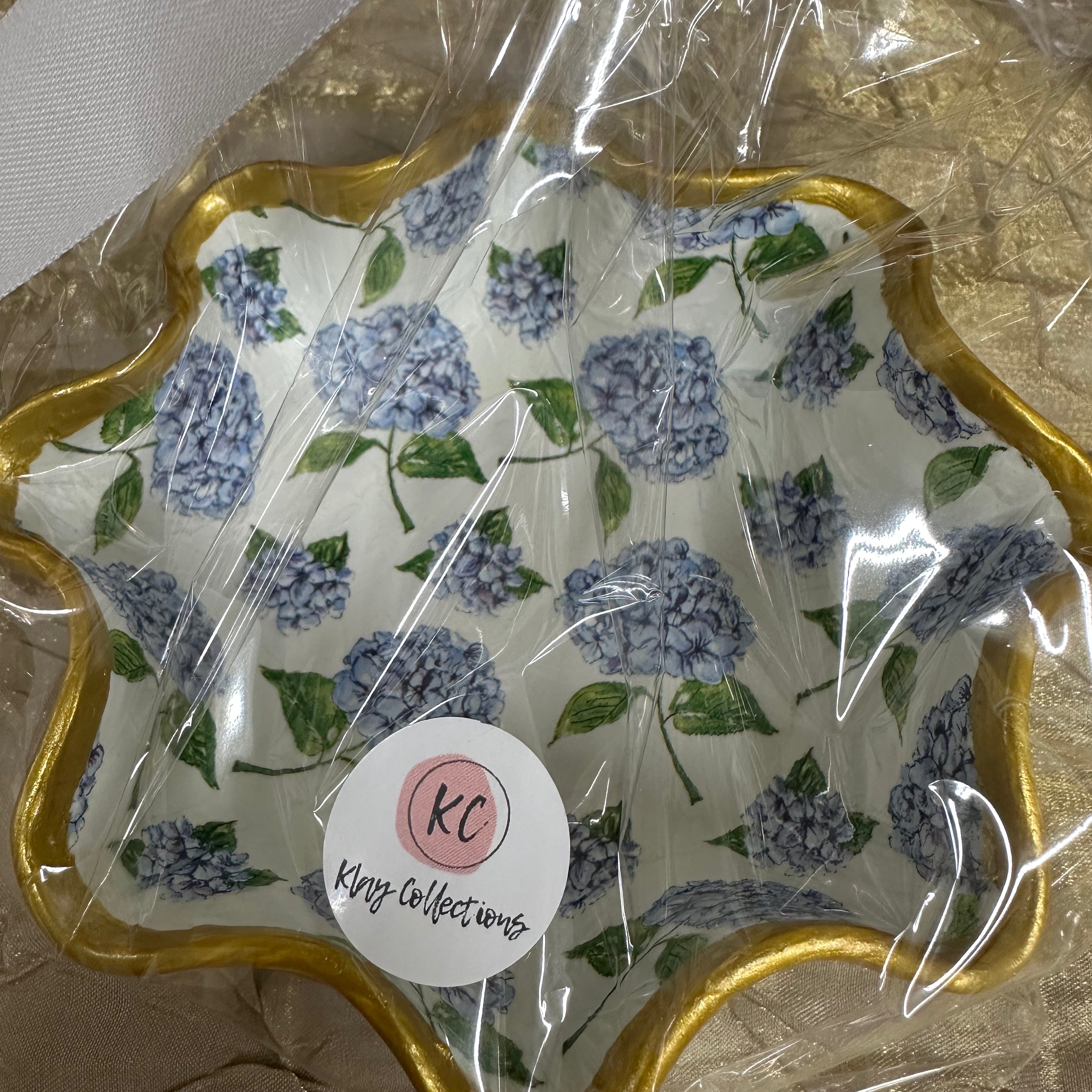 Decorative paper with floral design and gold border, wrapped in clear plastic with a visible brand label.