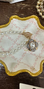 Jewelry dish with pearls and a ring on a wooden surface