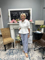 Woman standing in a room with a fireplace, chairs, and decorative elements.