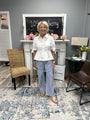 Woman standing in a living room with a fireplace and decorative elements.