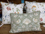 Decorative pillows with floral and bird patterns on a wooden surface.