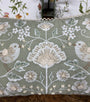 Decorative pillow with floral and bird patterns on a wooden surface.