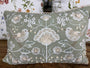 Decorative pillow with floral and bird patterns on a wooden surface.