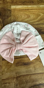 Baby hat with pink bow on a wooden surface
