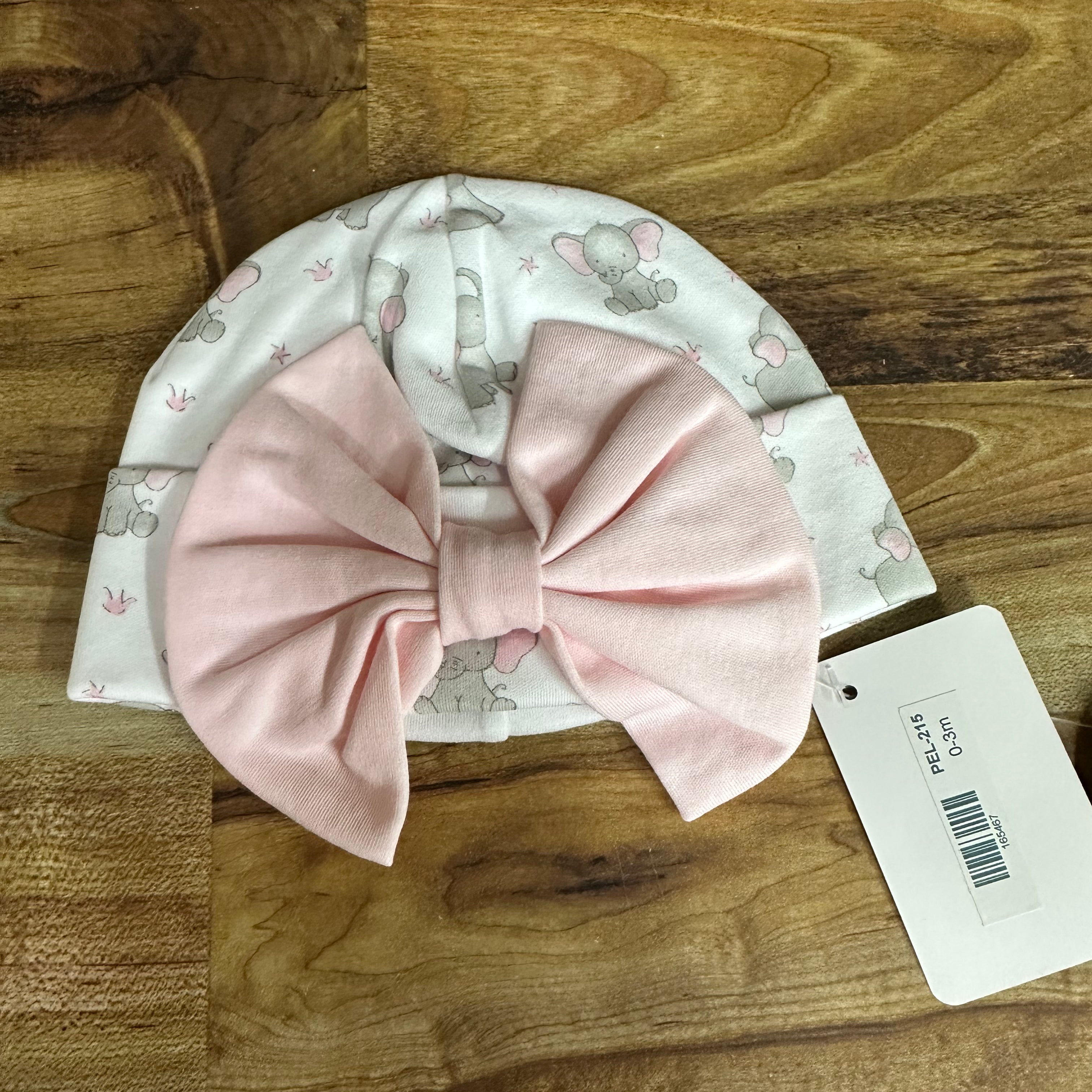 Baby hat with pink bow on a wooden surface