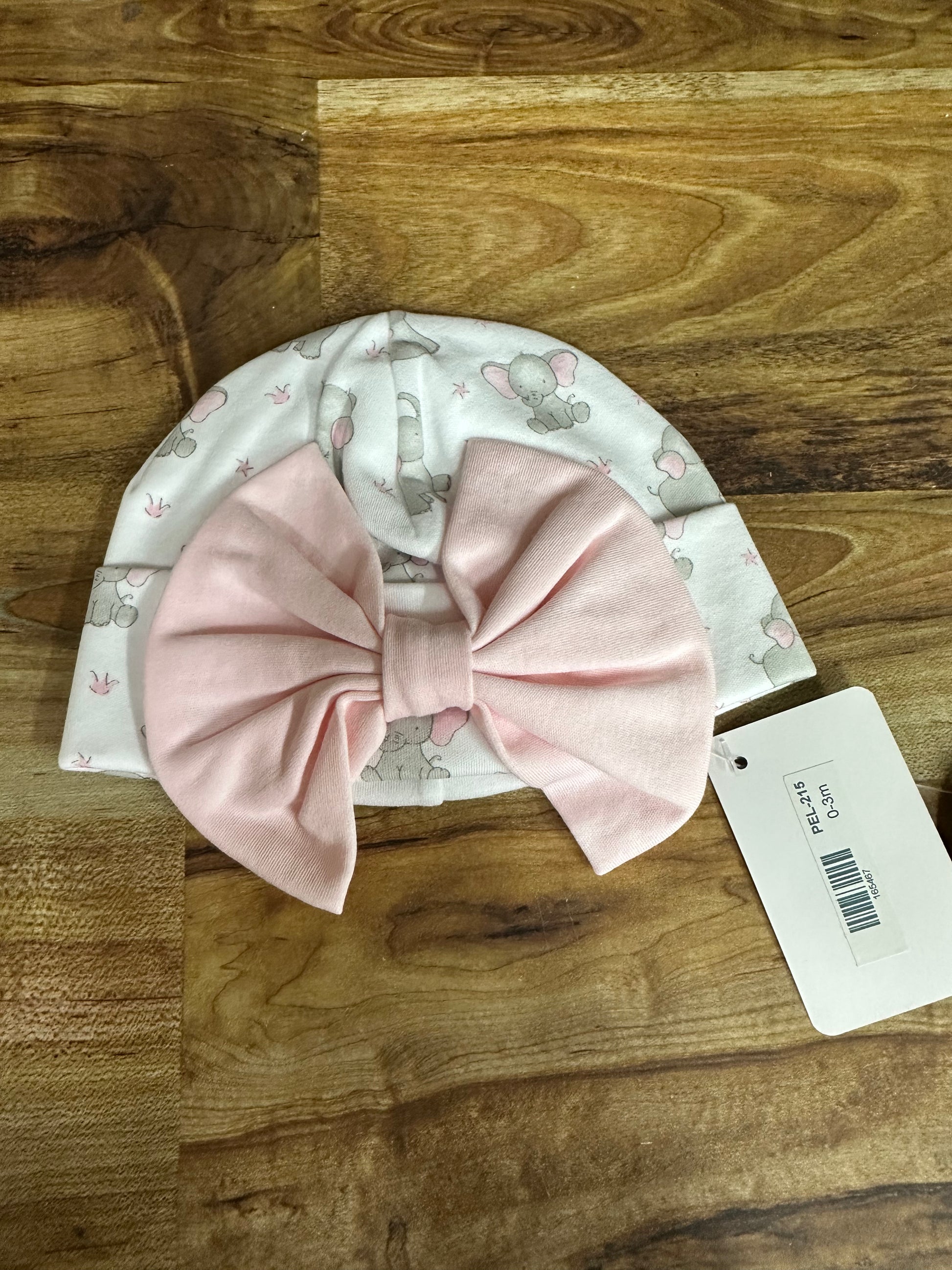 Baby hat with pink bow on a wooden surface