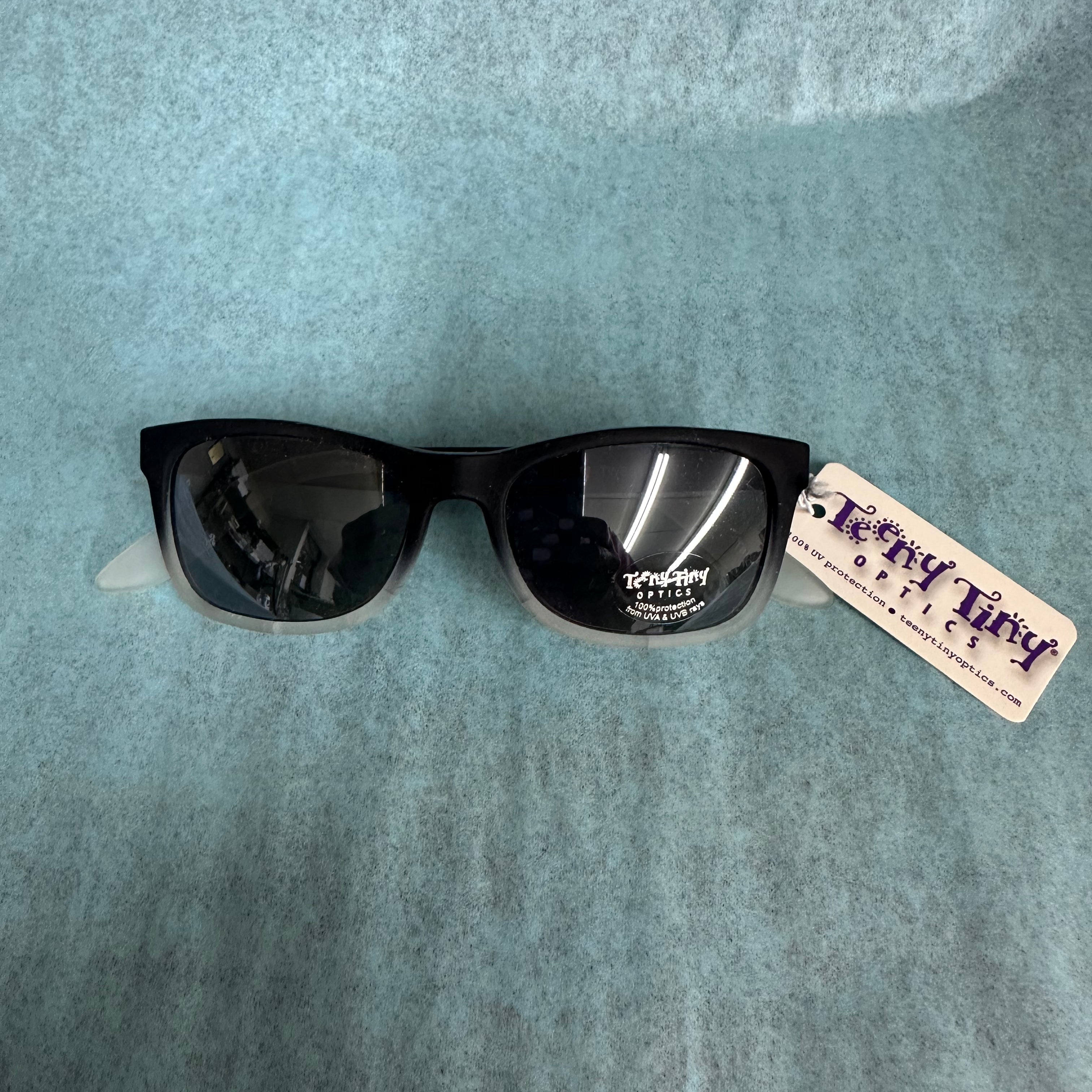 Black sunglasses with a tag on a gray background