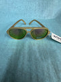 Gold-framed sunglasses with green lenses on a blue textured background