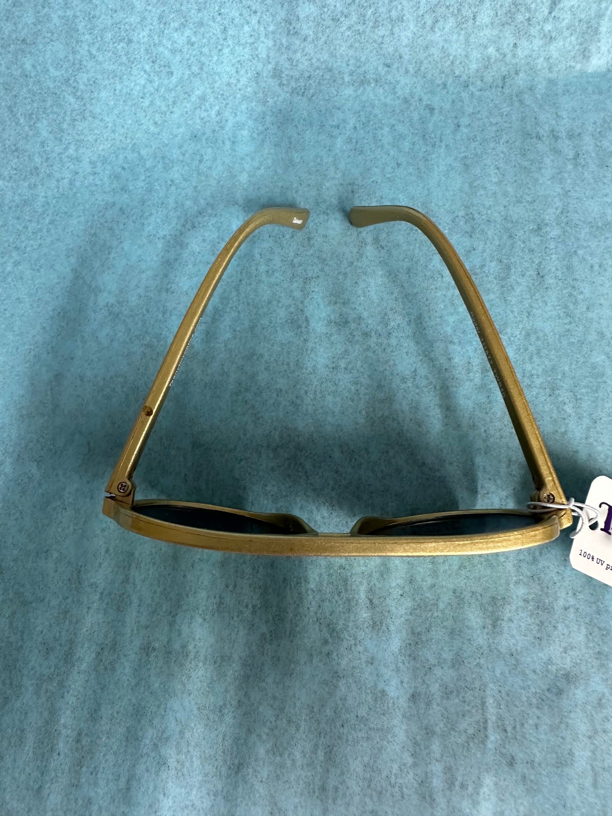 Gold-framed sunglasses on a blue textured background
