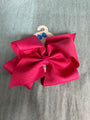 Large pink bow on a hanger against a gray background