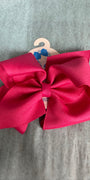 Large pink bow on a hanger against a gray background