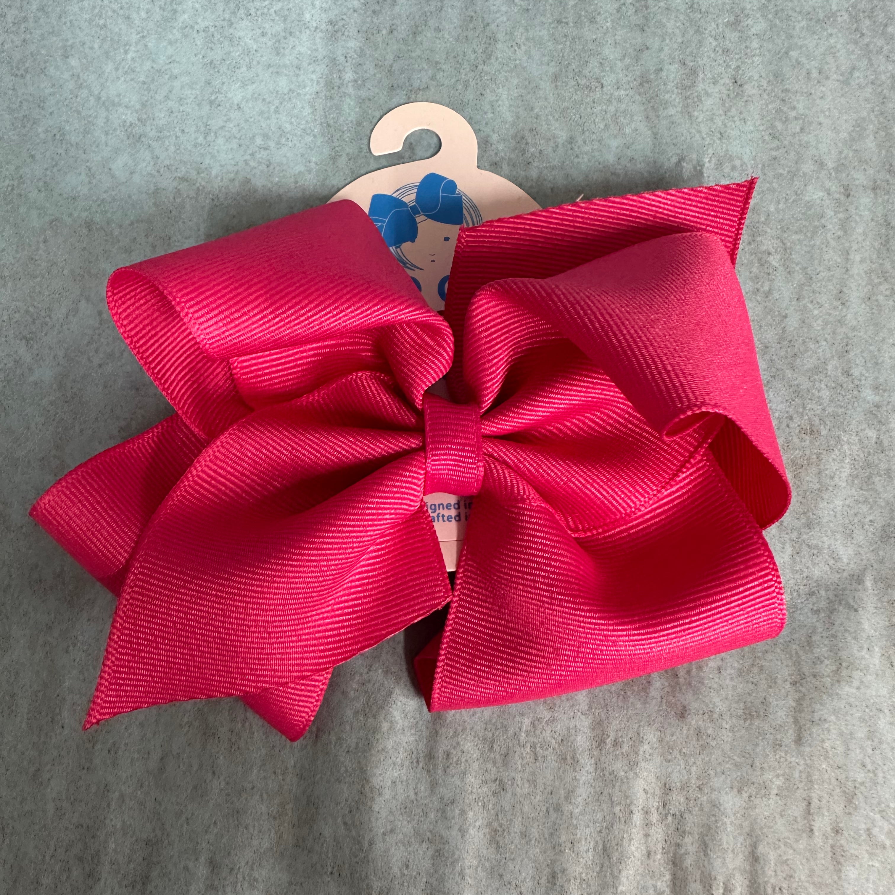 Large pink bow on a hanger against a gray background
