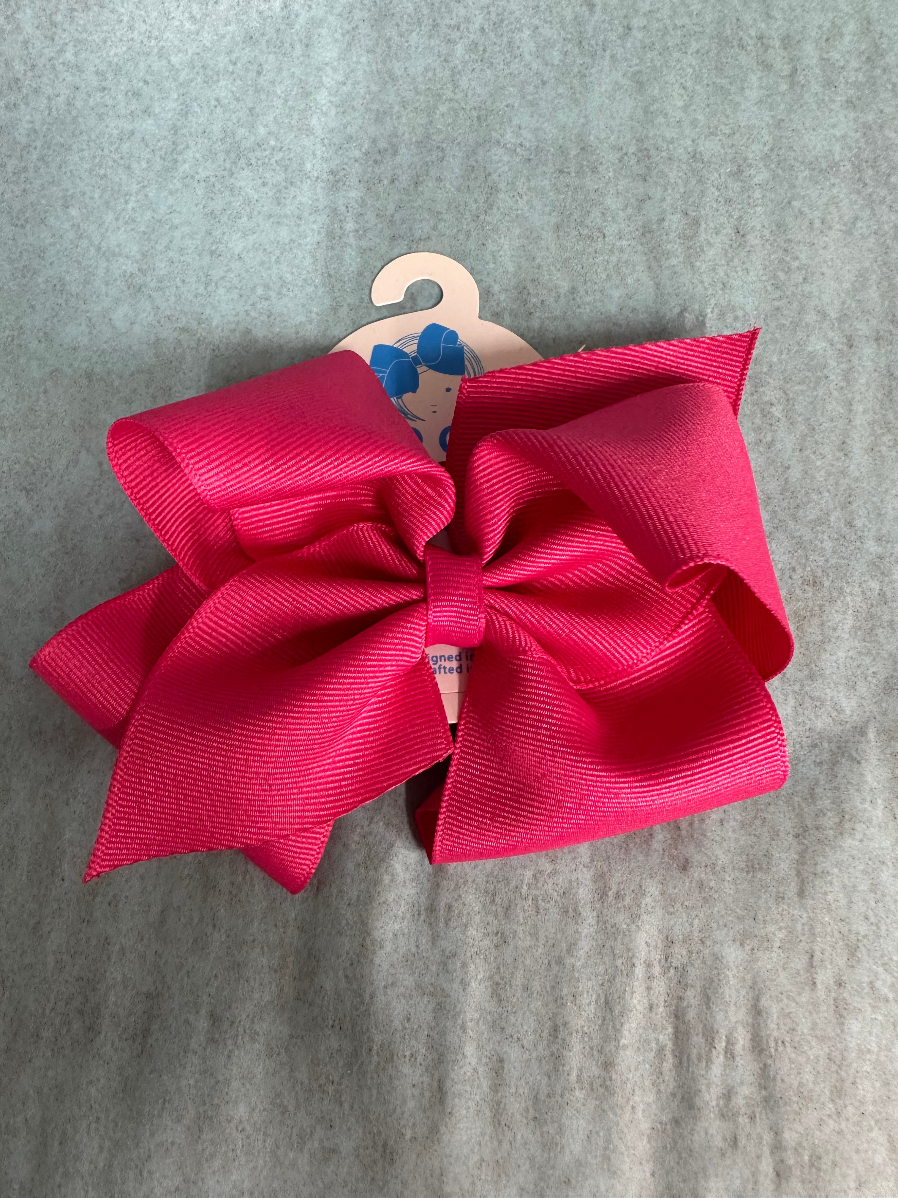 Large pink bow on a hanger against a gray background