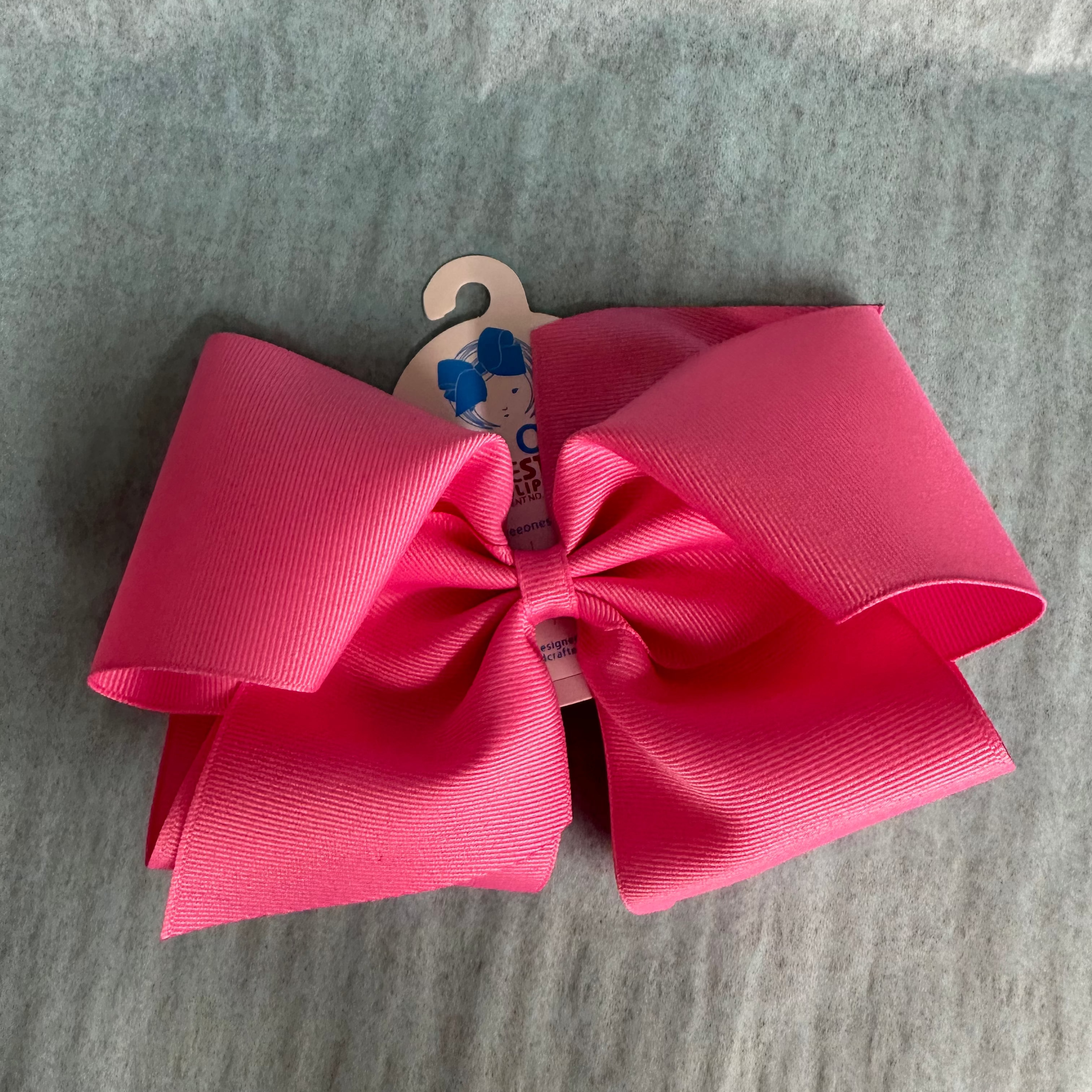 Large pink bow with a wooden hook on a gray surface