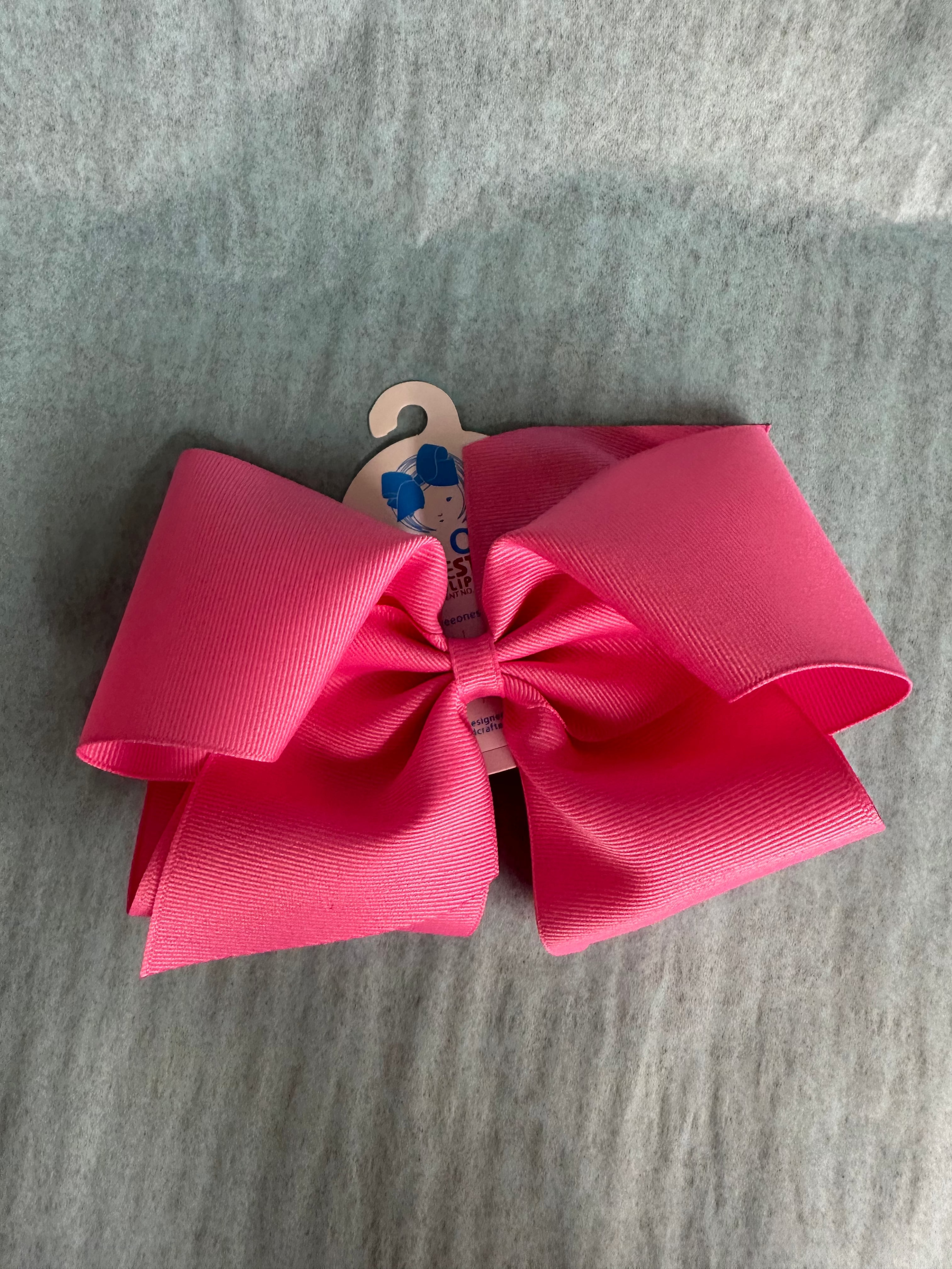 Large pink bow with a wooden hook on a gray surface