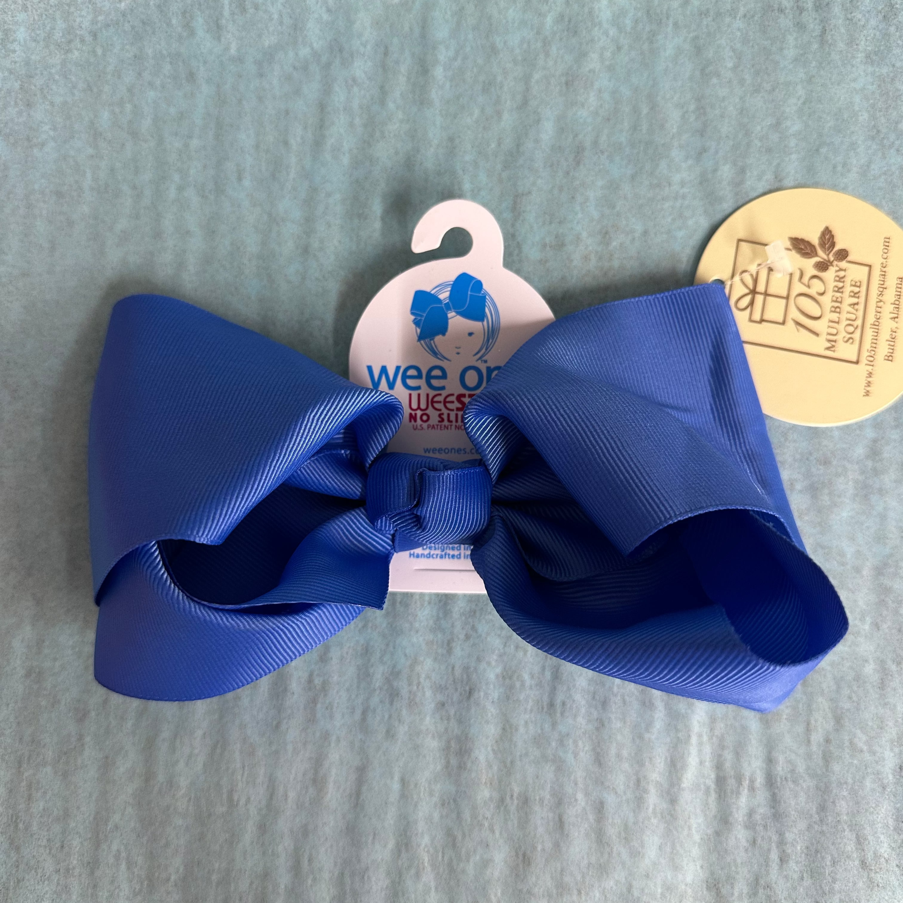 Blue hair bow with a tag on a gray background