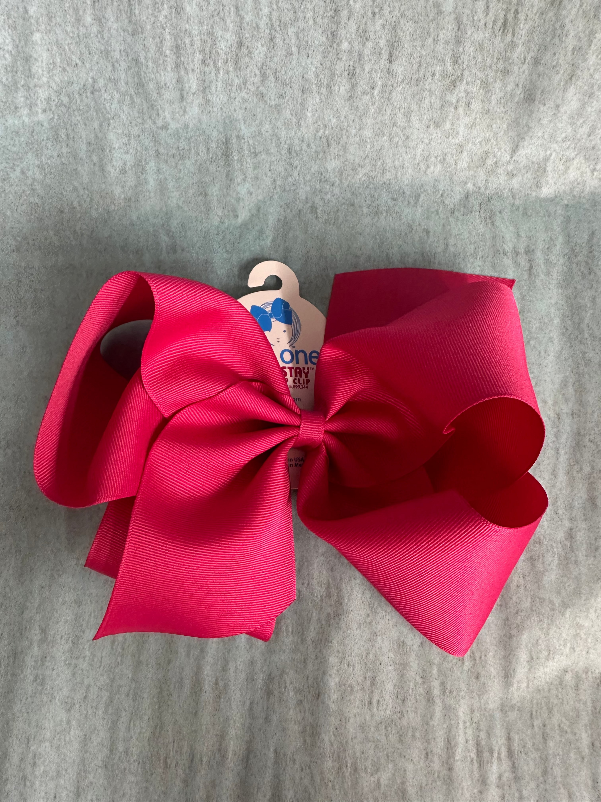 Hot pink hair bow with a heart on a gray background